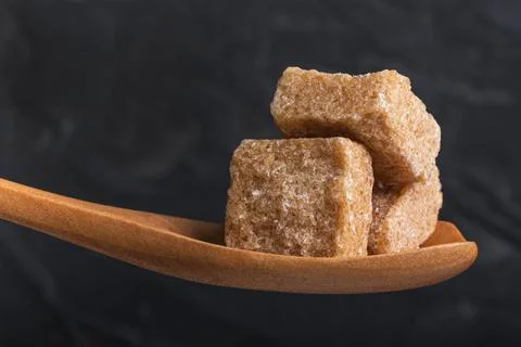 Three cubes of crushed cane sugar in a wooden spoon Stock-Fotos