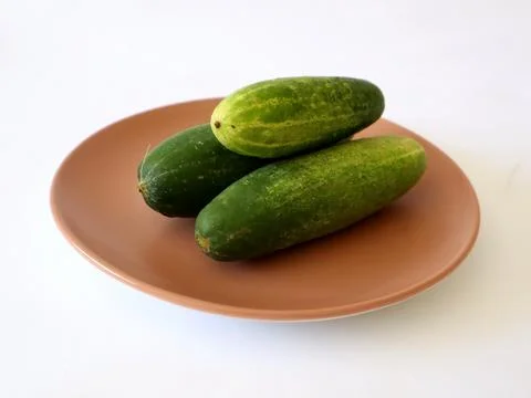Three cucumbers piled on a plate Stock Photos