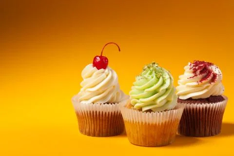 Three cupcakes isolated on orange background with copyspace Stock Photos