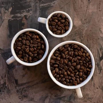 Three Cups are filled with roasted coffee beans. Flat Lay. White cups different Stock Photos