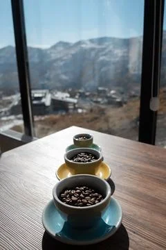 Three cups with brown coffee beans on wooden table Stock-Fotos