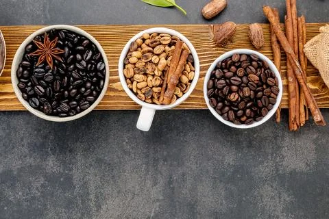 Three cups of coffee beans with cinnamon sticks and star anise Stock Photos