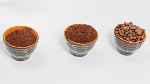 Three cups of coffee beans, ground coffee and cocoa for comparison. 스톡 사진