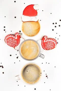 Three cups of coffee in shape of snowman with ginger cookie Santa hat and Stock Photos