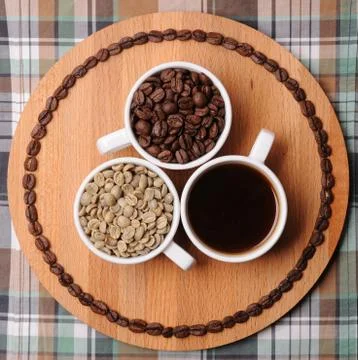 Three cups with different stages of coffee: green and roasted beans and espresso Foto stock