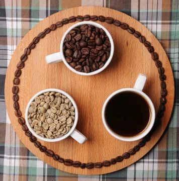 Three cups with different stages of coffee: green and roasted beans and espresso Stock Photos