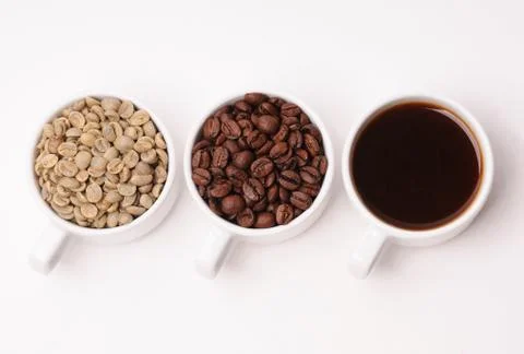 Three cups with different stages of coffee: green and roasted beans and espresso Stock Photos