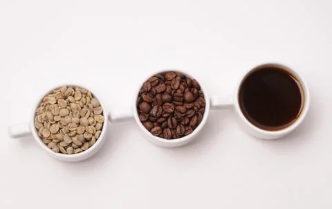 Three cups with different stages of coffee: green and roasted beans and espresso Stock Photos