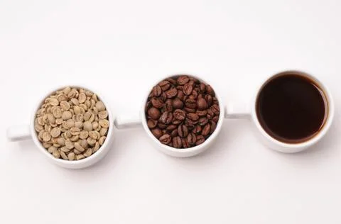Three cups with different stages of coffee: green and roasted beans and espresso Stock Photos