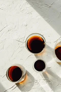 Three cups of fresh brewed coffee and glass cup on white cement background Stock-Fotos