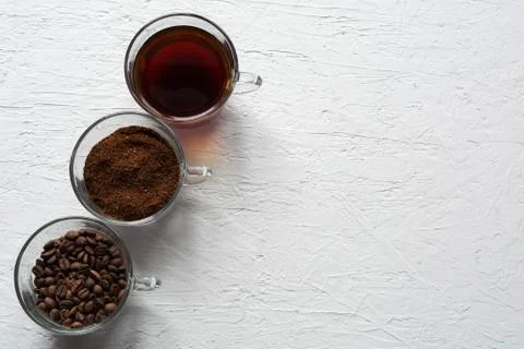 Three cups of ground coffee, coffee beans and brewed coffee in one row Stock Photos