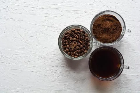 Three cups of ground coffee, coffee beans and brewed coffee in one row Stock Photos
