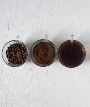 Three cups of ground coffee, coffee beans and brewed coffee in one row Stock Photos
