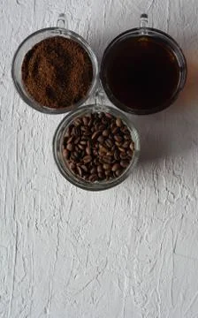 Three cups of ground coffee, coffee beans and brewed coffee in one row Stock Photos