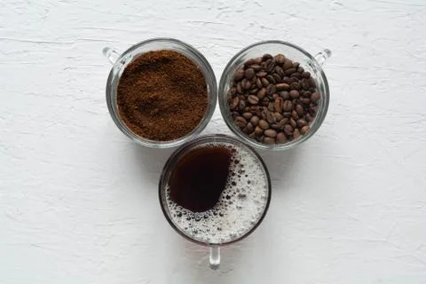 Three cups of ground coffee, coffee beans and brewed coffee in one row Stock Photos
