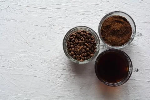 Three cups of ground coffee, coffee beans and brewed coffee in one row Stock Photos