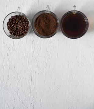 Three cups of ground coffee, coffee beans and brewed coffee in one row Stock Photos