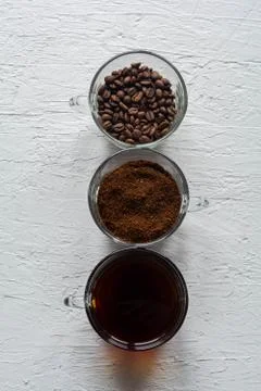 Three cups of ground coffee, coffee beans and brewed coffee in one row Stock Photos