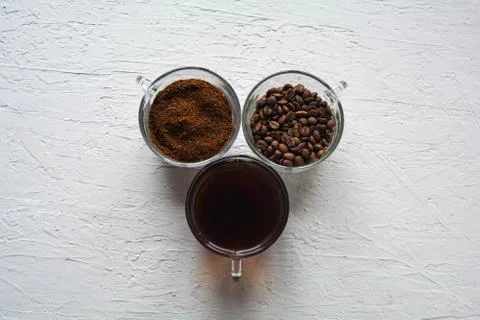 Three cups of ground coffee, coffee beans and brewed coffee in one row Stock Photos