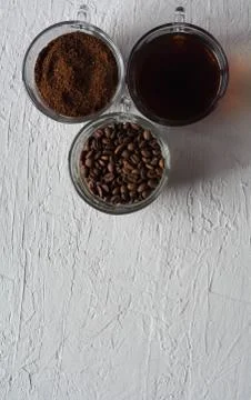 Three cups of ground coffee, coffee beans and brewed coffee in one row Stock Photos