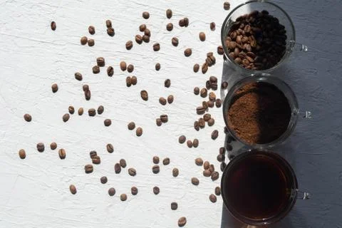 Three cups of ground coffee, coffee beans and brewed coffee in one row Stock Photos