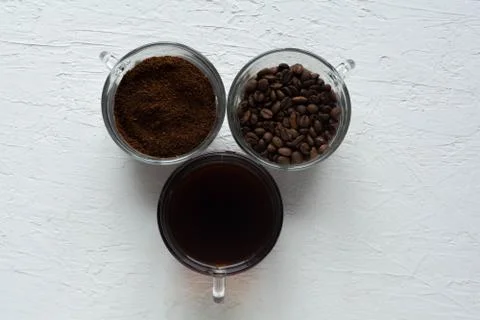 Three cups of ground coffee, coffee beans and brewed coffee in one row Stock Photos