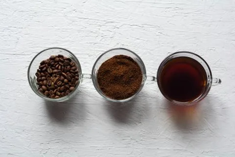 Three cups of ground coffee, coffee beans and brewed coffee in one row Stock Photos