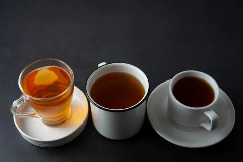 Three cups with hot tea drink on dark background, copy space. Tea time or tea Foto stock