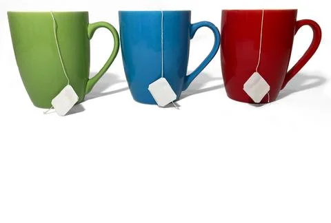 Three cups stand in a row on a white background. Green, red and blue cups. Stock Photos