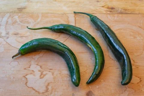 Three curved Chilaca peppers nesting on a weathered wood background, rustic Stock Photos