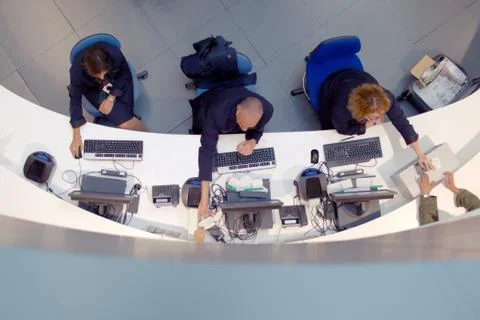 Three customer service agents working at a help desk at the airport. Stock Photos