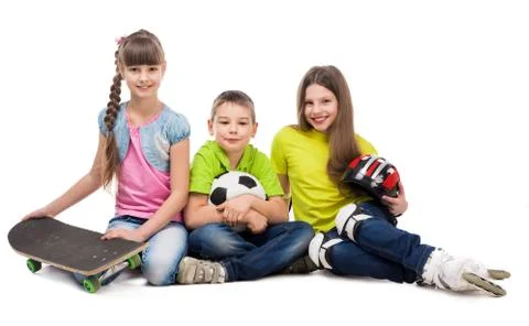 Three cute children sitting on the floor with sport equipment Foto stock