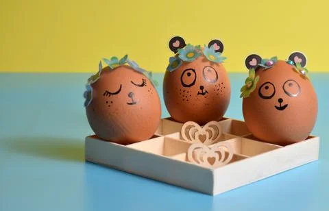 Three cute Easter eggs in a box on a yellow-blue background. Easter. Foto stock