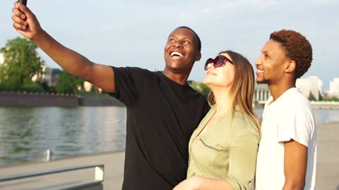 Three cute friends taking a selfie on a smartphone while on a bridge that Stock Footage 137115094