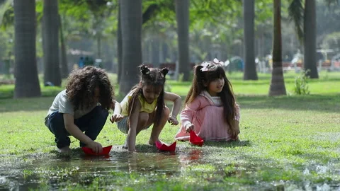 Three cute kids playing with paper boats in the park Stock Footage 239329017