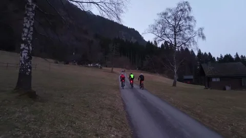 Three Cyclists Climbing Mountain Road at Dawn with Bike Lights 스톡 동영상 330242297