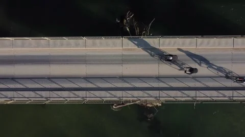Three cyclists ride across the bridge view from above Stock Footage 142766774