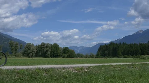 Three cyclists riding left to right, beautiful alpine panorama Stock Footage 118402575