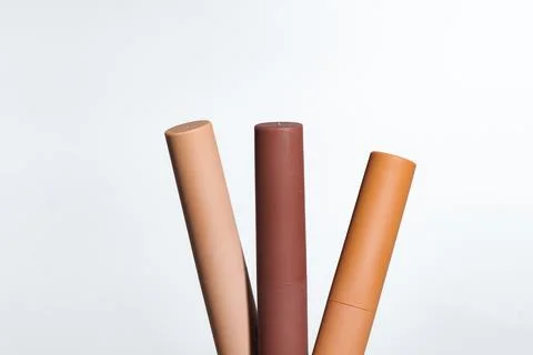 Three cylindrical makeup containers in varying shades of brown and tan agai.. Stock Photos