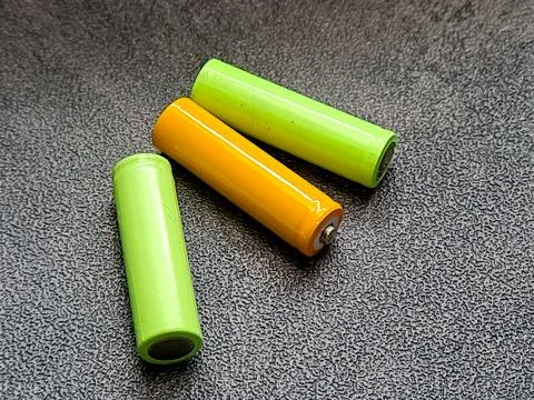 Three cylindrical objects, two vivid green and one bright orange, rest on a.. Foto stock
