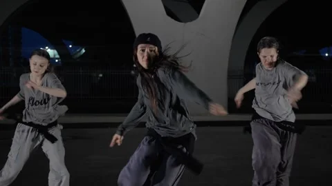 Three dancers move in unison under city bridge, their bodies flowing with rhythm Video stock 281556426