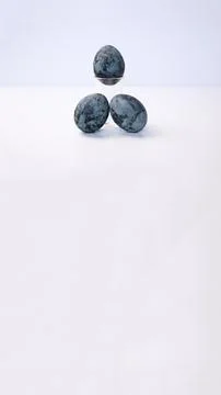 Three dark blue marbled Easter eggs styled on a clear glass stand against a.. Stock Photos