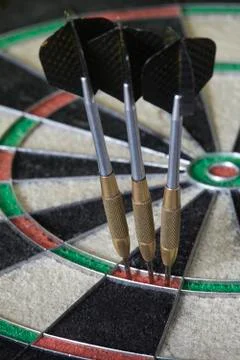Three darts on triple ring target of dartboard, concept of victory and goal a Stock Photos