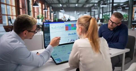 Three Data Analysts Review Financial Dashboard Together, Discussing Key Metri Stock Photos