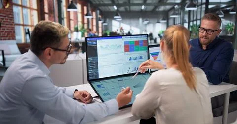 Three Data Analysts Working Together On Financial Dashboard Insights. Stock Photos