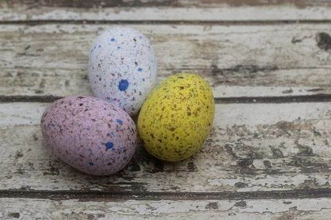 Three decorated chocolate eggs on rustic wood background Фото