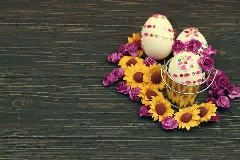 Three decorated easter eggs with spring flowers on wooden background Stock Photos