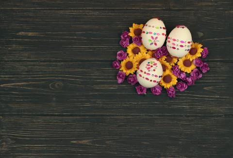 Three decorated easter eggs with spring flower on wooden background Stock Photos