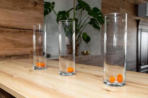 Three decorated glasses stand in a row on a natural wood table top. In the Stock Photos