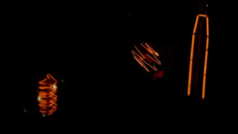 Three decorative filament light bulbs gradually switch on and off Stock Footage 127886548
